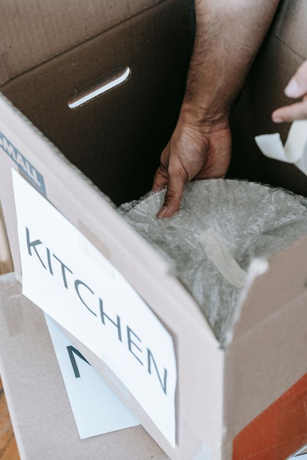 Artículos pequeños de cocina colocados cuidadosamente en una caja para mudanza
